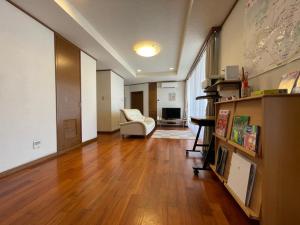 sala de estar con suelo de madera y silla en 民泊ありんくりん en Haebaru