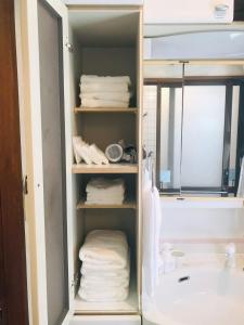 a bathroom cabinet with towels and a bath tub at 民泊ありんくりん in Haebaru