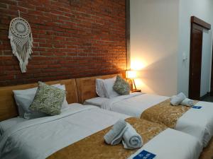 2 camas en una habitación con una pared de ladrillo en Coco Blu Villa en Singaraja