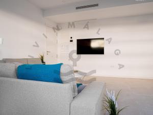 a living room with a couch and a tv on a wall at LivinMálaga Los Álamos Suites in Torremolinos
