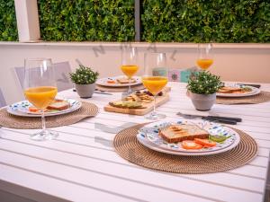 een tafel met borden en glazen sinaasappelsap bij LivinMálaga Los Álamos Suites in Torremolinos