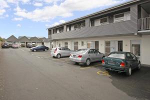 um grupo de carros estacionados num parque de estacionamento em frente a um edifício em Big Five Motel em Palmerston North