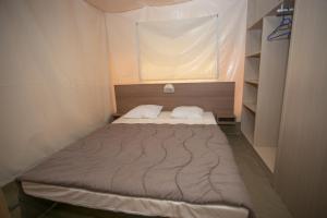 ein kleines Bett in einem kleinen Zimmer mit Fenster in der Unterkunft La Bastide in Mazères