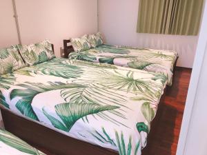 two twin beds in a room with palm leaves at The Wonder At Stay-Bentencho- in Osaka