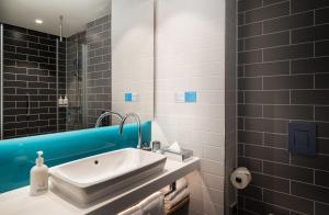 La salle de bains est pourvue d'un lavabo et d'un miroir. dans l'établissement Holiday Inn Express - Rosenheim, an IHG Hotel, à Rosenheim