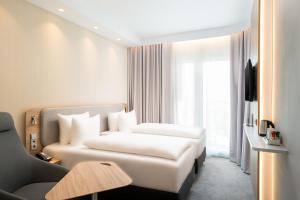 um quarto de hotel com uma cama branca e um sofá em Holiday Inn Express - Rosenheim, an IHG Hotel em Rosenheim