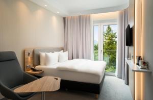 une chambre d'hôtel avec un lit, une chaise et une fenêtre dans l'établissement Holiday Inn Express - Rosenheim, an IHG Hotel, à Rosenheim
