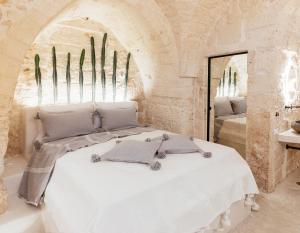 a bedroom with a white bed and a mirror at Alesia Luxury Cave in Ostuni +30 photos