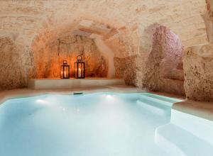 a hot tub in a stone room with two candles at Alesia Luxury Cave in Ostuni