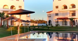 een zwembad met parasols voor een gebouw bij Smart Holiday Cabo Negro in Cabo Negro