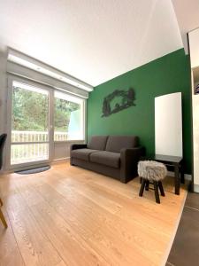 a living room with a couch and a green wall at Superbe appartement vue sur la forêt in Les Angles