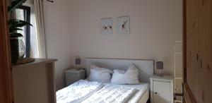 Schlafzimmer mit einem Bett mit weißer Bettwäsche und Kissen in der Unterkunft Neumühle Ferienwohnung 2 in Lutzerath