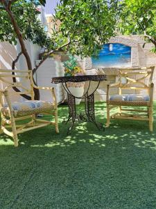 a patio with two chairs and a table and a table and benches at Zia Mia B&b in Olbia