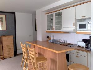 eine Küche mit weißen Schränken und einer Theke mit Stühlen in der Unterkunft Zinnowitz Residenz Sanssouci in Zinnowitz