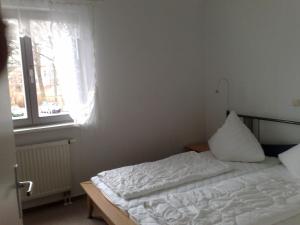 ein Schlafzimmer mit einem weißen Bett und einem Fenster in der Unterkunft Zinnowitz Residenz Sanssouci in Zinnowitz + 3 Fotos