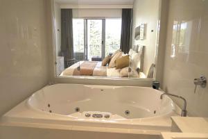 eine weiße Badewanne im Bad mit Spiegel in der Unterkunft Peppers Balé Luxury Beach Accommodation Kingscliff - privately let in Kingscliff