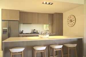 a kitchen with a counter with stools and a clock at Peppers Balé Luxury Beach Accommodation Kingscliff - privately let in Kingscliff