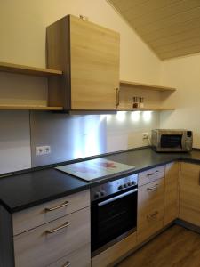 a kitchen with wooden cabinets and a black stove top oven at Strandurlaub am Felsenmeer in Modautal