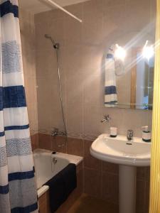 La salle de bains est pourvue d'un lavabo, d'une baignoire, d'un lavabo et d'un miroir. dans l'établissement APARTAMENTO EDISON,PARKING, PISCINA VISTAS AL MAR, Castellón de la Plana