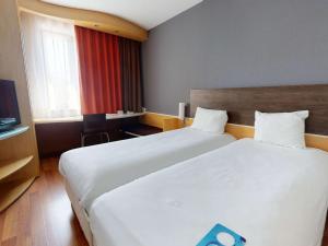 a hotel room with two beds and a television at Ibis Bratislava Centrum in Bratislava