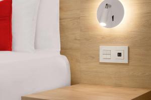 1 dormitorio con cama y interruptor de luz en Ramada by Wyndham Madrid Tres Cantos, en Tres Cantos