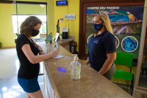 two women wearing face masks standing at a counter at Hotel Pousada Arauna in Bonito