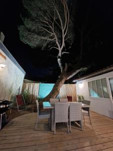 um deque com uma mesa, cadeiras e uma árvore em Villa Bagatelle à 300m de la plage centrale, 3 chambres em Arcachon