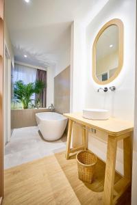 bagno con vasca, lavandino e specchio di Hotel Leonor Conil a Conil de la Frontera