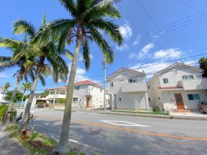 une rue avec des maisons et des palmiers dans l'établissement グランディオーソ沖縄ヴィラ恩納3, à Onna