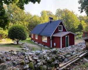 a red house with a pile of rocks in front of it at Skogsgläntan in Näsum