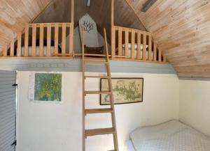a loft bed in a tiny house with a bed at Skogsgläntan in Näsum