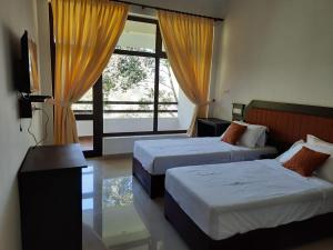 a bedroom with two beds and a large window at Spring and Valley View in Thekkady