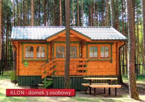 a cabin in the woods with a picnic table and a bench at Ośrodek Wypoczynkowy Kormoran Niesulice in Niesulice