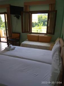 a bedroom with a white bed and a window at Roula Rooms in Stratoni