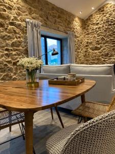 uma sala de estar com uma mesa de madeira e uma parede de pedra em Casa María da Retratista em Muxía