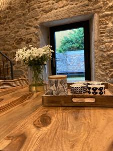 a wooden table with a vase of flowers and a window at Casa María da Retratista in Muxia