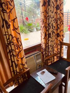 Zimmer mit einem Tisch und einem Fenster mit Vorhängen in der Unterkunft House of lights in Solan