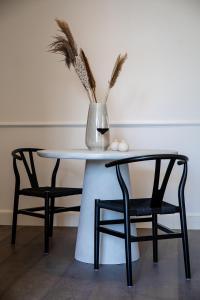 stół z dwoma krzesłami i wazonem na nim w obiekcie Villa Ostinato w Ostendzie
