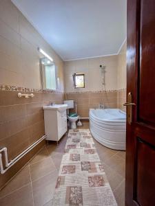 a bathroom with a tub and a toilet and a sink at Casa BiaFlor in Rucăr