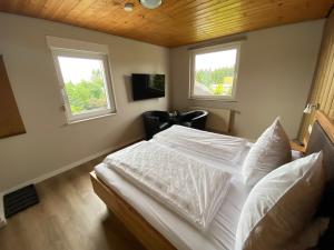 1 Schlafzimmer mit einem weißen Bett und 2 Fenstern in der Unterkunft Berghotel Lenneplätze Winterberg in Winterberg