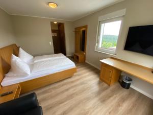 a small bedroom with a bed and a television at Berghotel Lenneplätze Winterberg in Winterberg