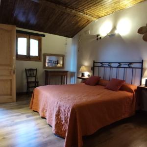 TortelláにあるLa casa de l'Aviのベッドルーム1室(オレンジ色のベッドカバー付きの大型ベッド1台付)