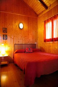 um quarto com uma cama vermelha num quarto de madeira em Cabañas de San Bartolomé em Villahermosa del Río