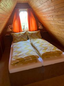 a bed in a small room with orange curtains at Ferienhaus Busch in Bünsdorf