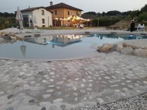 a pool of water with rocks and a house in the background at Agriturismo Madre Terra in Narni