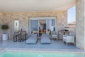 un patio con piscina, mesa y sillas en Sofia Suite, a seafront hideaway !, en Panormos Rethymno