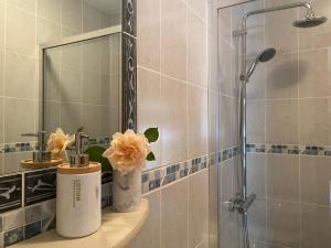 ein Badezimmer mit einer Dusche und einem Waschbecken mit Blumen in der Unterkunft Quinta dos Mouras B&B in Rebordões