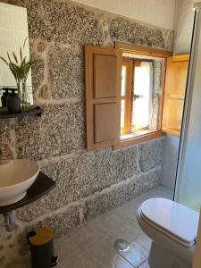 ein Bad mit einem Waschbecken, einem WC und einem Fenster in der Unterkunft Quinta dos Mouras B&B in Rebordões