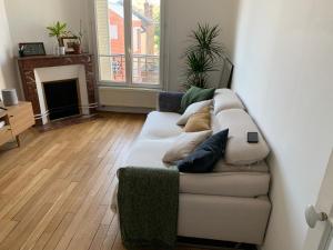 - un salon avec un canapé blanc et des oreillers dans l'établissement Appartement tout confort à 10 min de La Défense, à Colombes