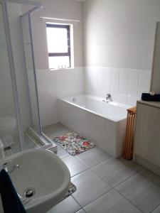 a white bathroom with a tub and a sink at @ the reef Holiday Home in St. Helena Bay +34 photos